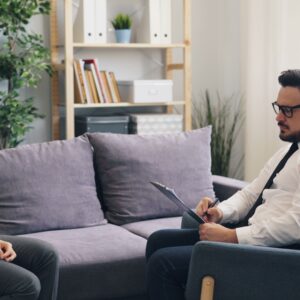 A therapy session showing a woman consulting a professional therapist in a cozy office environment.