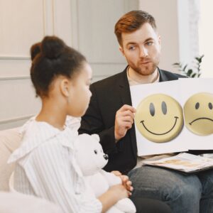 A therapist uses emotion cards to help a child express feelings during a counseling session.