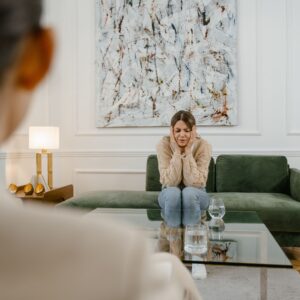 A woman in a counseling session, looking distressed and contemplative, indoors.